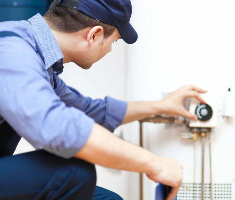 Electrician or Plumber adjusting a water heater gauge